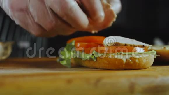 厨师的双手把切肯片放在三明治上视频的预览图