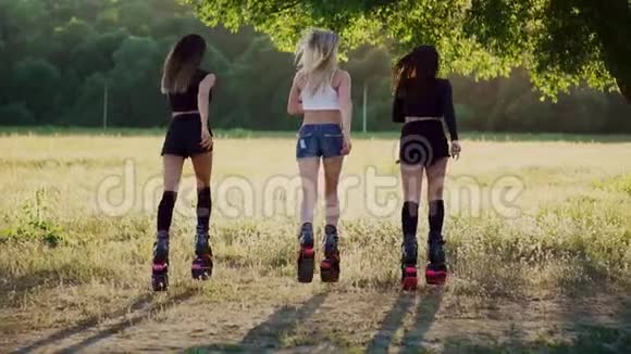 日落时分三个穿着靴子有泉水的女孩在夏季公园里跑步视频的预览图