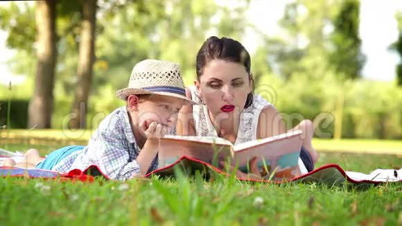 妈妈在公园野餐时给儿子读了一本书视频的预览图