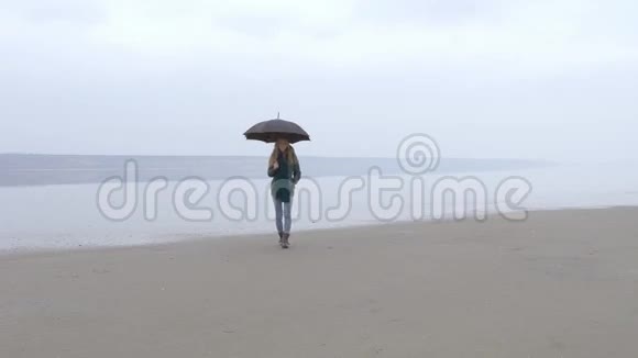 带着雨伞的女孩走向沙滩上的摄像机笑了起来视频的预览图