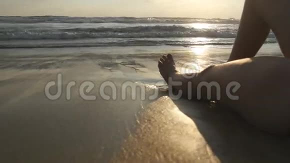 一双女孩的脚躺在海滩上海水冲刷着晒黑的女性腿和身体美丽的年轻女子视频的预览图
