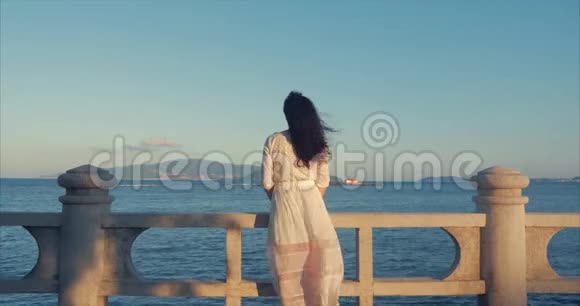 美丽的高加索女人在日落时看海景年轻美丽的女孩享受大自然看着海洋视频的预览图