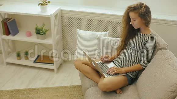 快乐少女在沙发上使用笔记本电脑视频的预览图