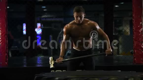 运动型肌肉型健身男子用铁锤敲击车轮轮胎健身男子健美视频的预览图