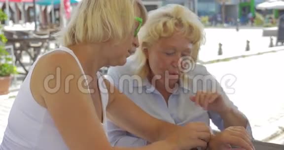 街头咖啡馆的高级女性使用智能手表视频的预览图