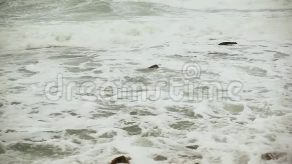 在石滩上缓慢移动的泡沫波视频的预览图