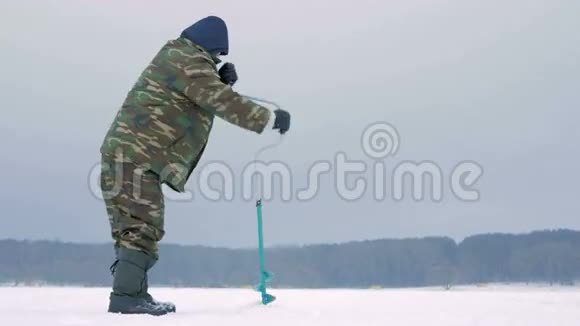 冬天在河上钓鱼一个人在冰上钻一个洞视频的预览图