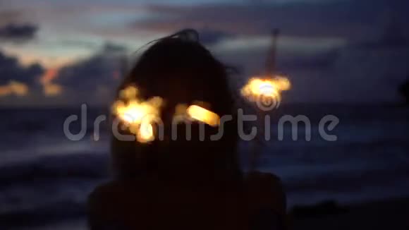 黄昏时分在海滩上燃放烟花的幸福女人特写视频的预览图