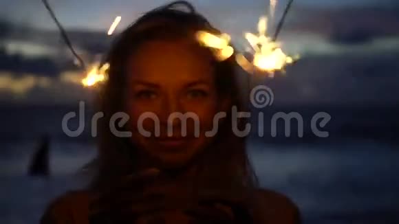 黄昏时分在海滩上燃放烟花的幸福女人特写视频的预览图