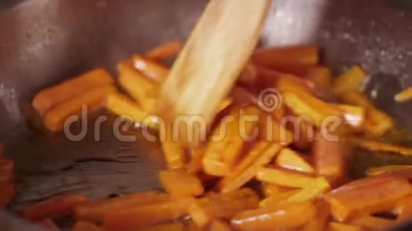 在煎锅上炸胡萝卜木铲搅动蔬菜煎锅里的蔬菜橙色视频的预览图