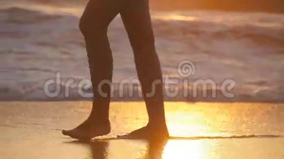 日落时女性赤脚在海边行走日出时年轻女子沿着海边的腿女孩视频的预览图