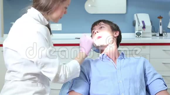 女性牙医做常规检查对微笑的男性病人视频的预览图