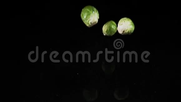 布鲁塞尔葡萄甘蓝黑背景下落入水中的蔬菜视频的预览图