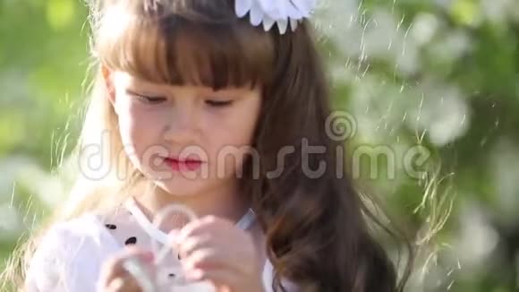 一个穿着白色衣服的女孩通过小音频耳机听音乐视频的预览图