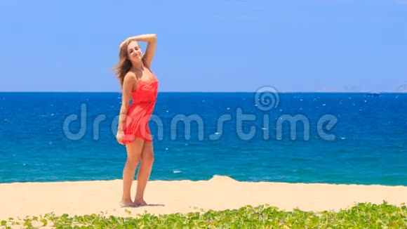 红色的金发女孩光着脚站在沙滩上光滑的头发视频的预览图