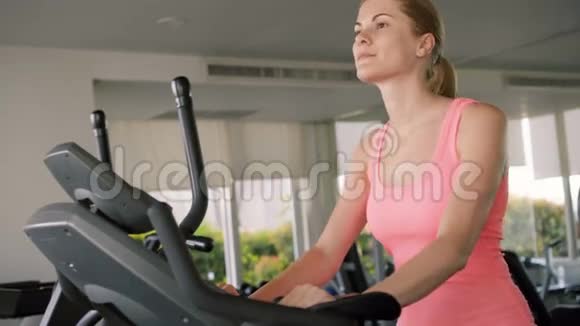 漂亮的健康的活跃的运动的年轻女人在健身房锻炼在天鹅绒模拟器上锻炼视频的预览图