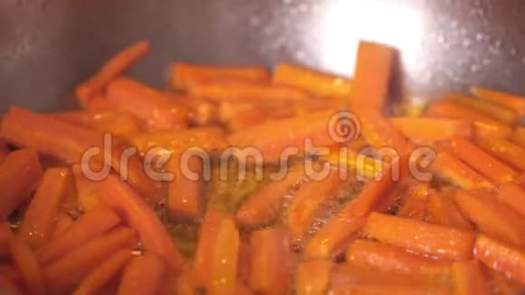 在煎锅上炸胡萝卜橙色胡萝卜在煎锅里凑近木铲搅动蔬菜很接近视频的预览图
