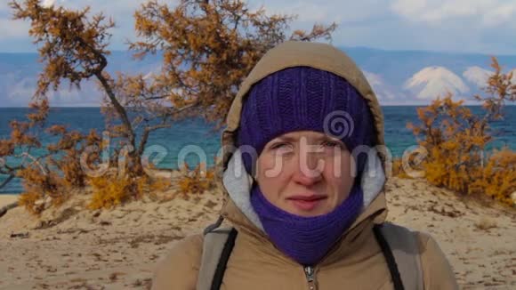 一个穿夹克衫头罩的女孩站在海边的肖像视频的预览图