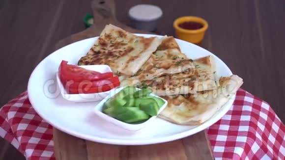 以黄瓜和番茄切片为原料在苏格兰花纹织物上旋转的土耳其传统的Gozleme皮塔土豆视频的预览图