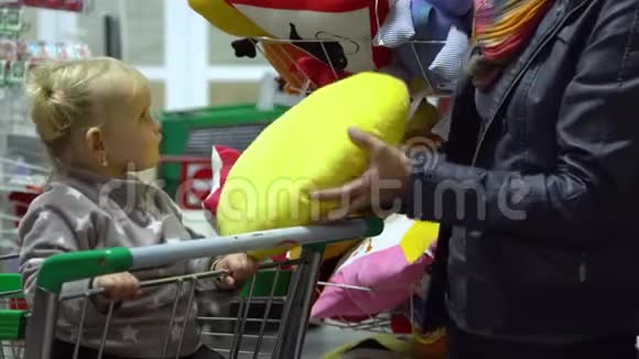 一个年轻的女人带着一个孩子在超市选择商品妈妈在手推车上驾驶一个小女孩妈妈和女儿视频的预览图