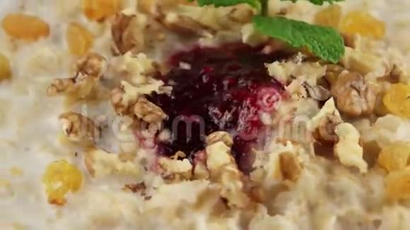 健康早餐燕麦粥葡萄干核桃和牛奶循环视频的预览图