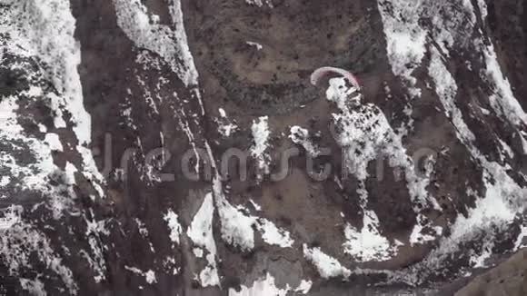 滑翔伞在白雪覆盖的岩石背景下降落视频的预览图