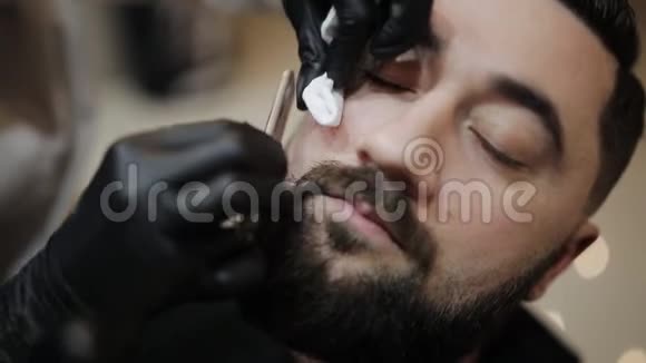理发店胡须的剃须过程师父用老式直剃刀做一个理发胡须客户视频的预览图