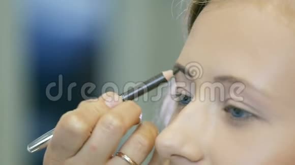 专业化妆师用蜡笔描画金发模特的眉毛视频的预览图