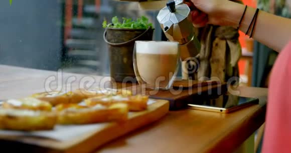 女人在4k咖啡馆的杯子里倒咖啡视频的预览图