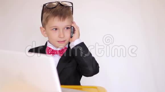 可爱的孩子扮演商人集中精力工作在电话里交谈成功视频的预览图