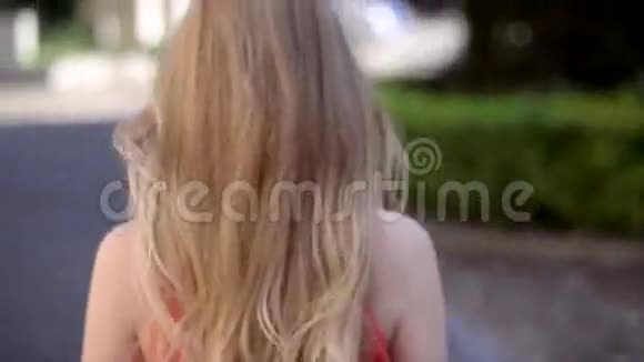 美丽的年轻女孩走着漂亮的女孩穿着红色的裙子走着穿过镜头从镜头视频的预览图