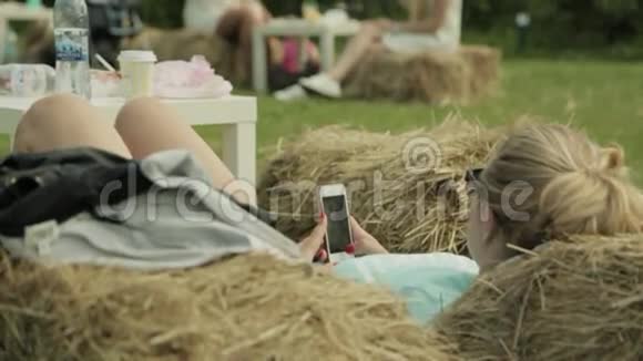 快乐的女孩躺在公园的草地上在电话里看书视频的预览图