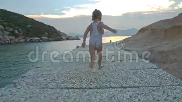 小女孩在日落的落基路沿岸奔跑视频的预览图