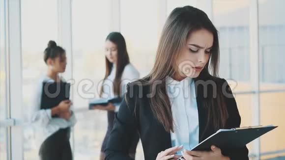 美丽的黑发商务女性穿着白色西装手里拿着文件夹在户外视频的预览图