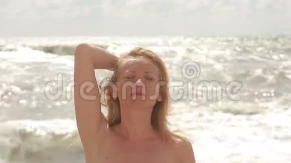 海滩上的金发女孩对着镜头微笑视频的预览图