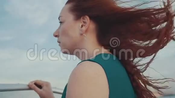 红发女孩穿着裙子在摩托艇上看着地平线美丽的夏日夕阳视频的预览图