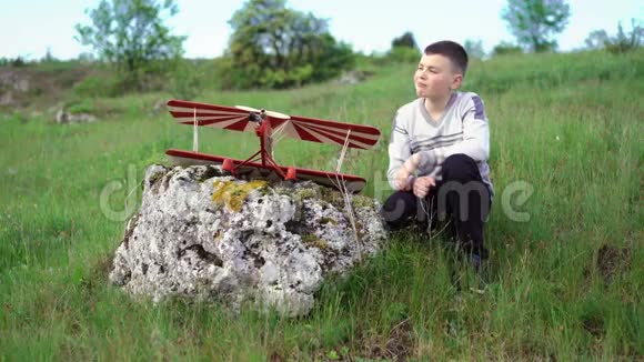 小男孩坐在石头上的玩具飞机附近4k视频的预览图