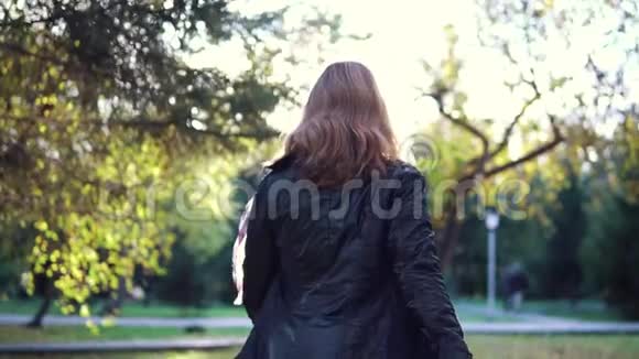 年轻漂亮的女人走在秋天的公园里女孩打开相机后景慢动作视频的预览图