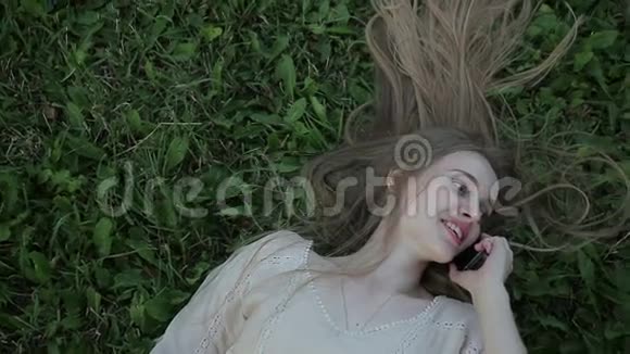 美女躺在草地上打电话的画像视频的预览图