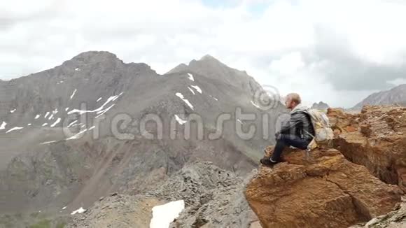 山顶上的人坐在岩石上看着村子里美好的日出视频的预览图