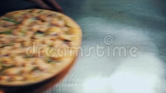 女性手把披萨放在木盘上放在厨房的金属桌上视频的预览图