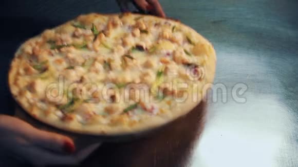 女人的手把比萨饼放在木盘上放在厨房的金属桌上视频的预览图