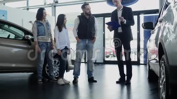 汽车推销员向年轻的家庭介绍他们的新车视频的预览图