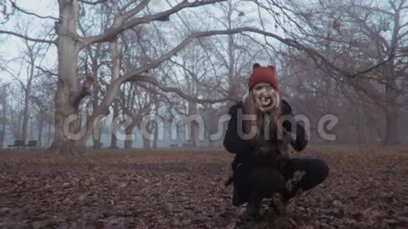 在雾蒙蒙的公园里漂亮的金发女人玩树叶视频的预览图