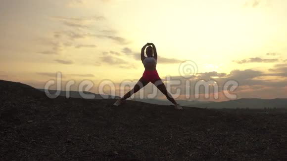 肌肉发达的女人的剪影完美的身体伸展户外日落健身理念视频的预览图