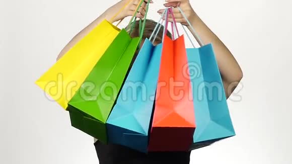 漂亮的女孩带着五颜六色的包裹购物白色的慢动作视频的预览图