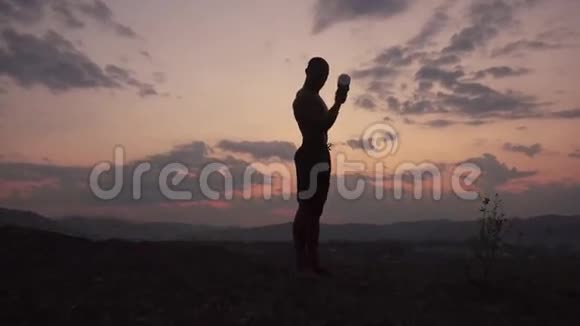 英俊的非洲裔美国肌肉运动员举哑铃在粉红色日落天空背景户外培训视频的预览图