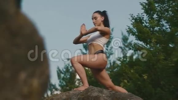 美丽强壮的黑发女人在悬崖边户外练习瑜伽放松夜空背景视频的预览图