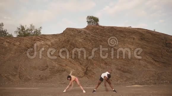 适合混合种族夫妇在石头海滩户外锻炼深色头发的女人伸展身体视频的预览图