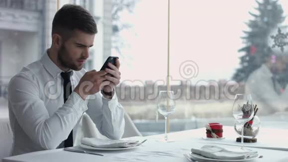 快乐的年轻人坐在咖啡馆里浏览智能手机视频的预览图